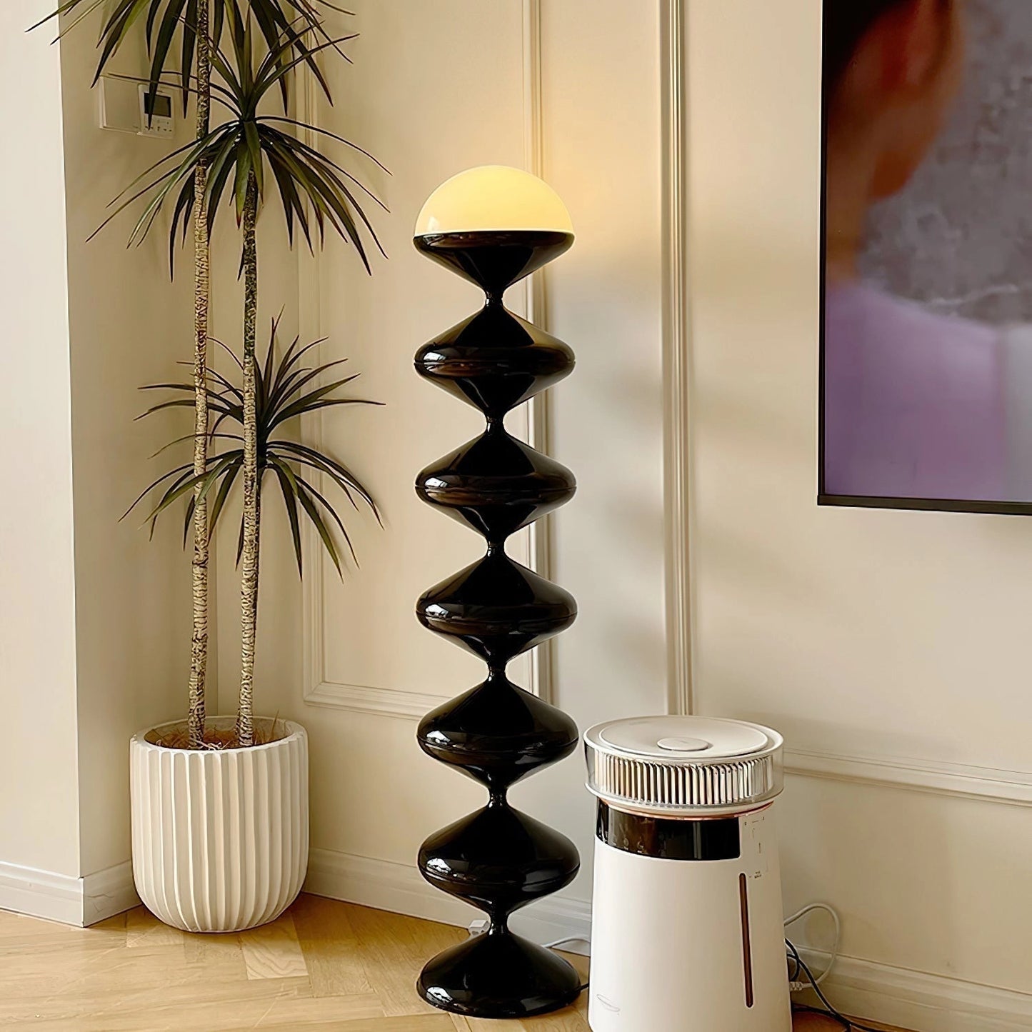 Modern elegant white floor lamp with a twisted gourd design, placed in a stylish interior setting with wooden shelves, potted plants, and a rectangular wall decor.