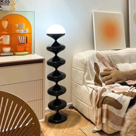 Modern elegant floor lamp with twisted gourd design, featuring a wooden base and an orange lampshade, placed in a stylish interior setting with shelves and cabinetry.