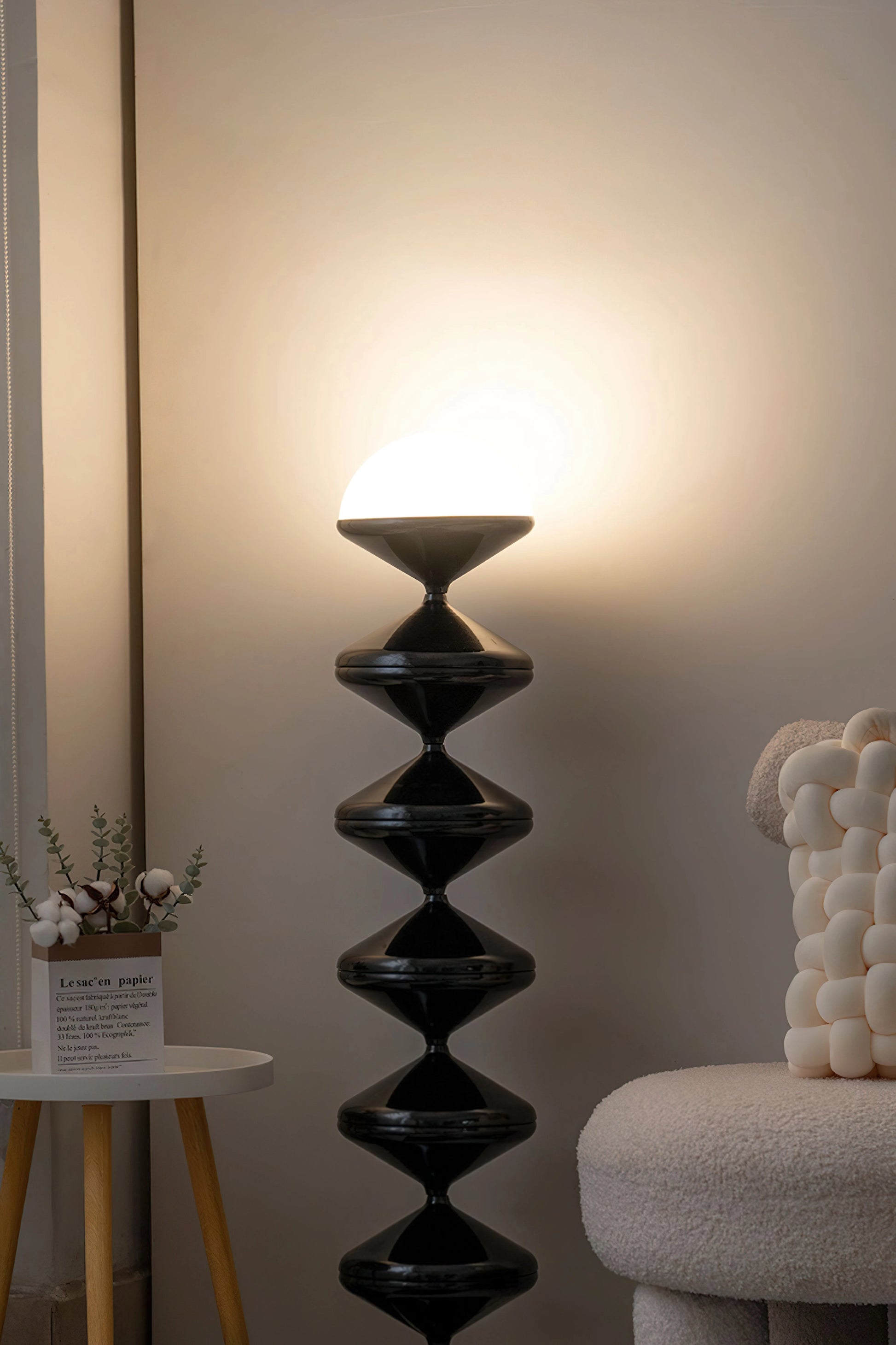 Modern floor lamp with a twisted gourd design, featuring white and wooden elements, illuminating a stylish interior with elegant lighting.