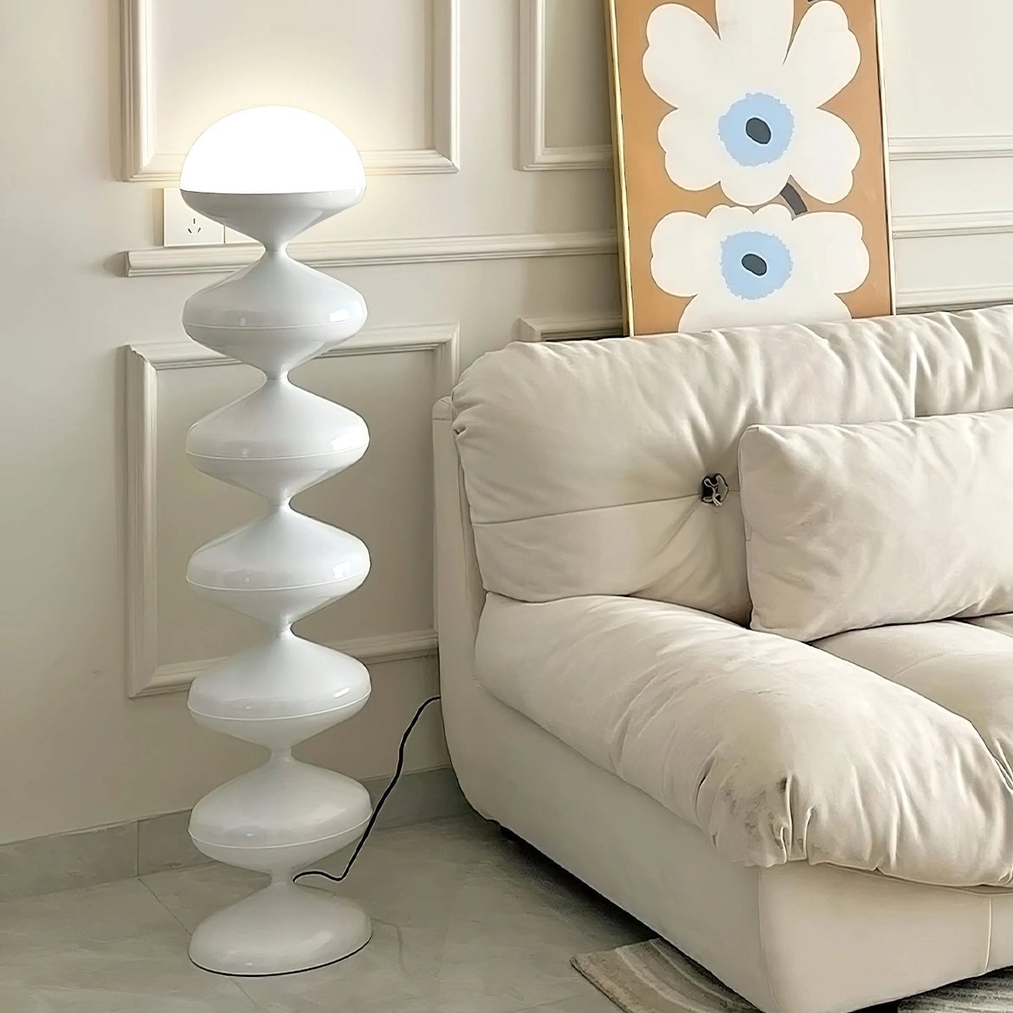Modern elegant floor lamp with twisted gourd design placed in a stylish living room with a white couch and wooden furniture.