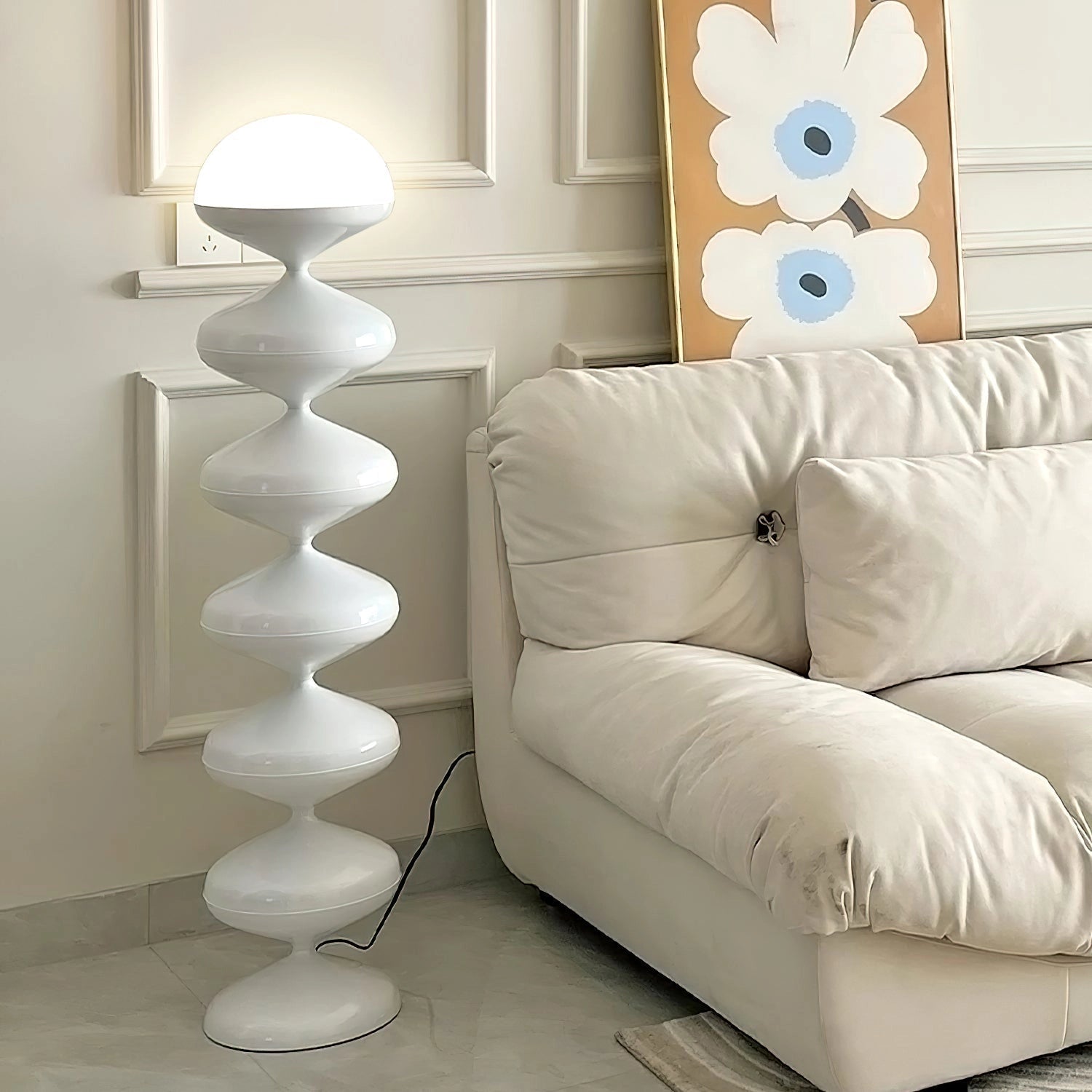Modern elegant floor lamp with twisted gourd design placed in a stylish living room with a white couch and wooden furniture.