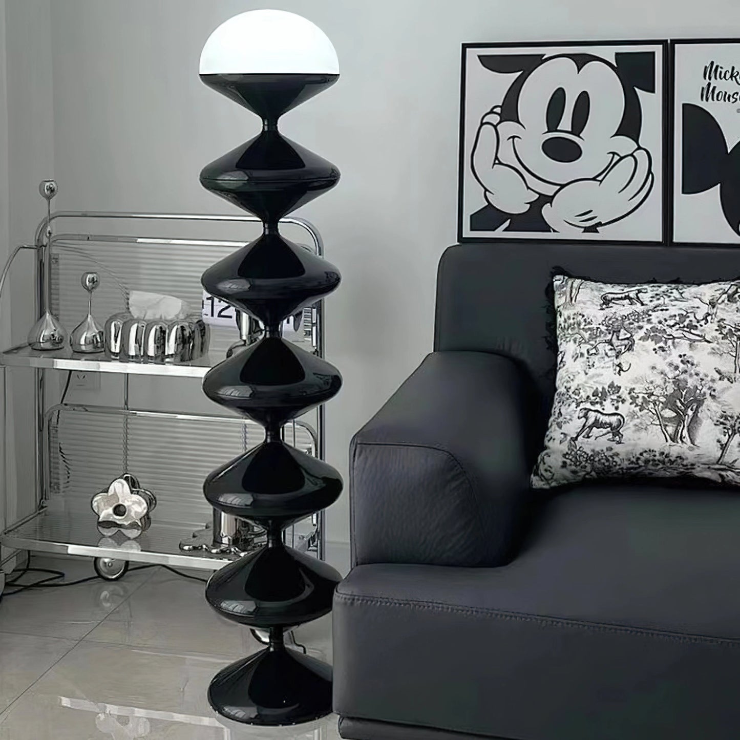 Modern elegant floor lamp with twisted gourd design in a stylish living room with black and grey interior decor and wooden shelving.