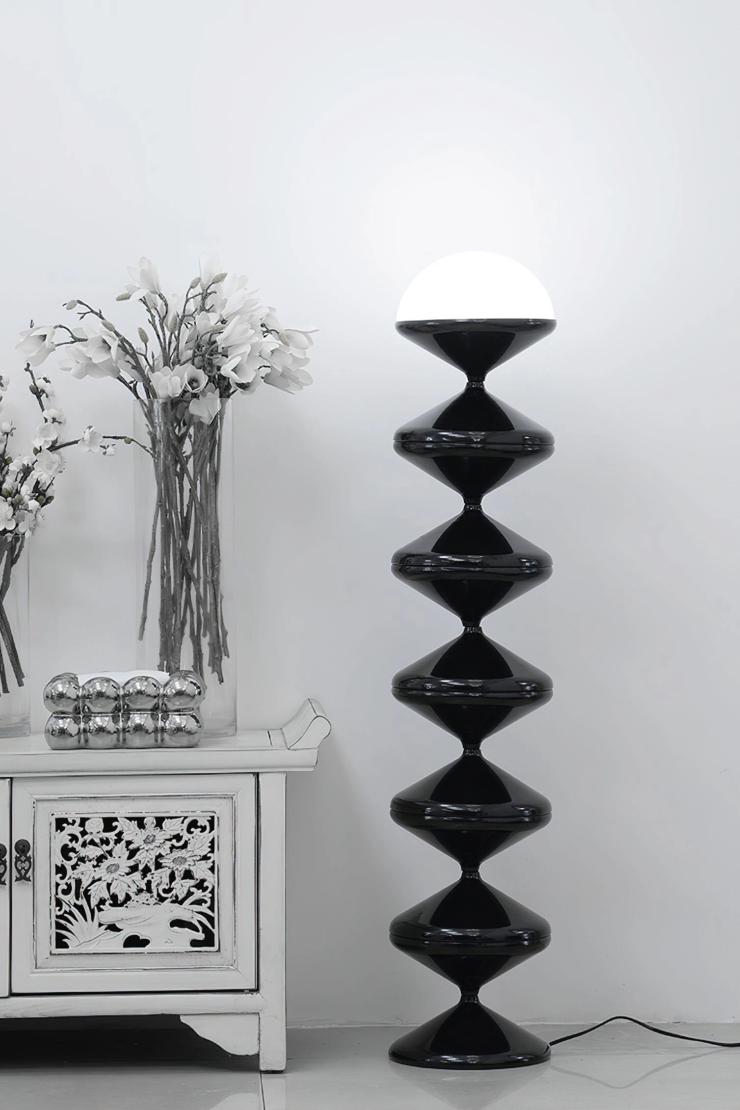 Modern elegant floor lamp with twisted gourd design, surrounded by wooden shelves and decorative plants.