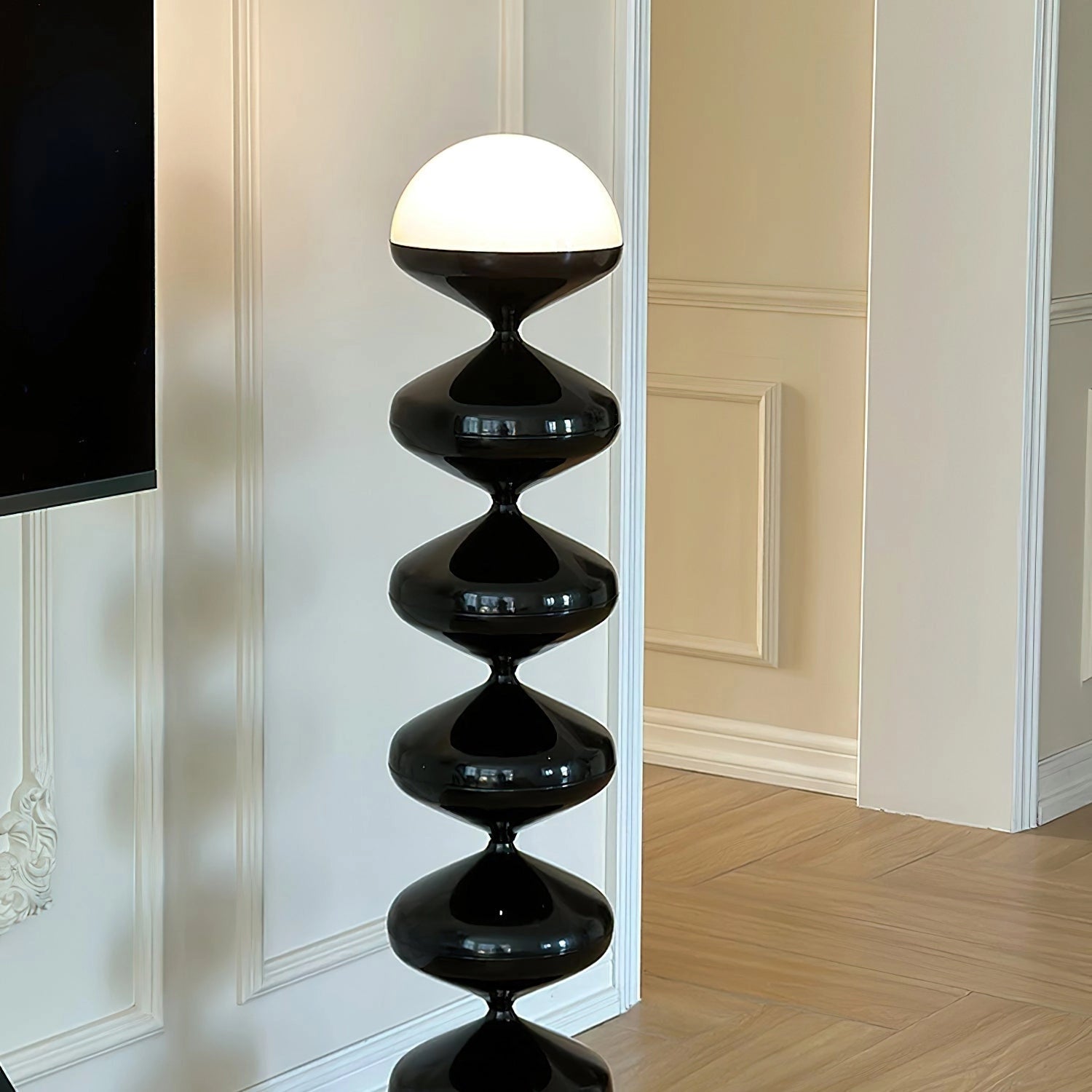Modern floor lamp with twisted gourd design next to wooden shelving unit and hardwood flooring.