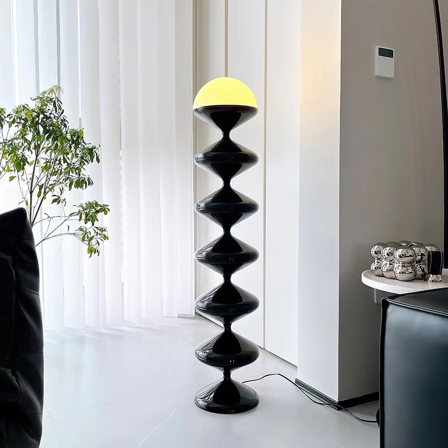 Modern elegant floor lamp with twisted gourd design beside shelving unit with plants in a stylishly designed interior room.