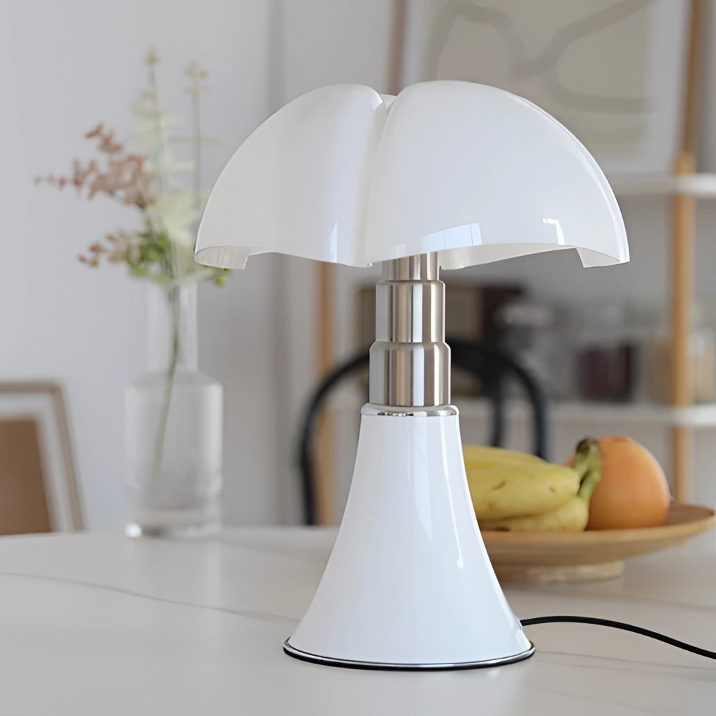 A white floral design table lamp with adjustable height and LED light on a wooden table, surrounded by interior decor elements such as plants and linens, set against hardwood flooring.