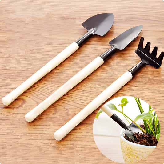 Gardening tool set with durable iron and wood handles placed on a wooden surface, surrounded by a potted plant and various gardening accessories.