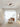 Modern geometric aluminum pendant light with LED technology hanging in a stylish interior with wooden flooring, large windows, and contemporary furniture.