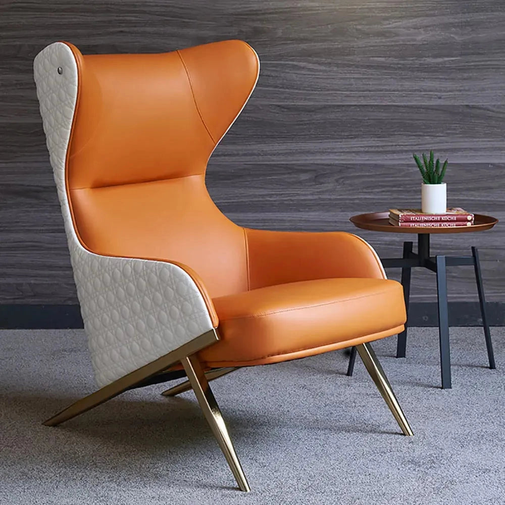 Orange geometric wingback accent chair with a gold trestle base, featuring armrests and comfortable cushioning, displayed on a wooden floor with a plant in the background.