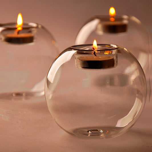 Glass candle holder with a lit tealight candle inside, showcasing the warm glow of the flame.