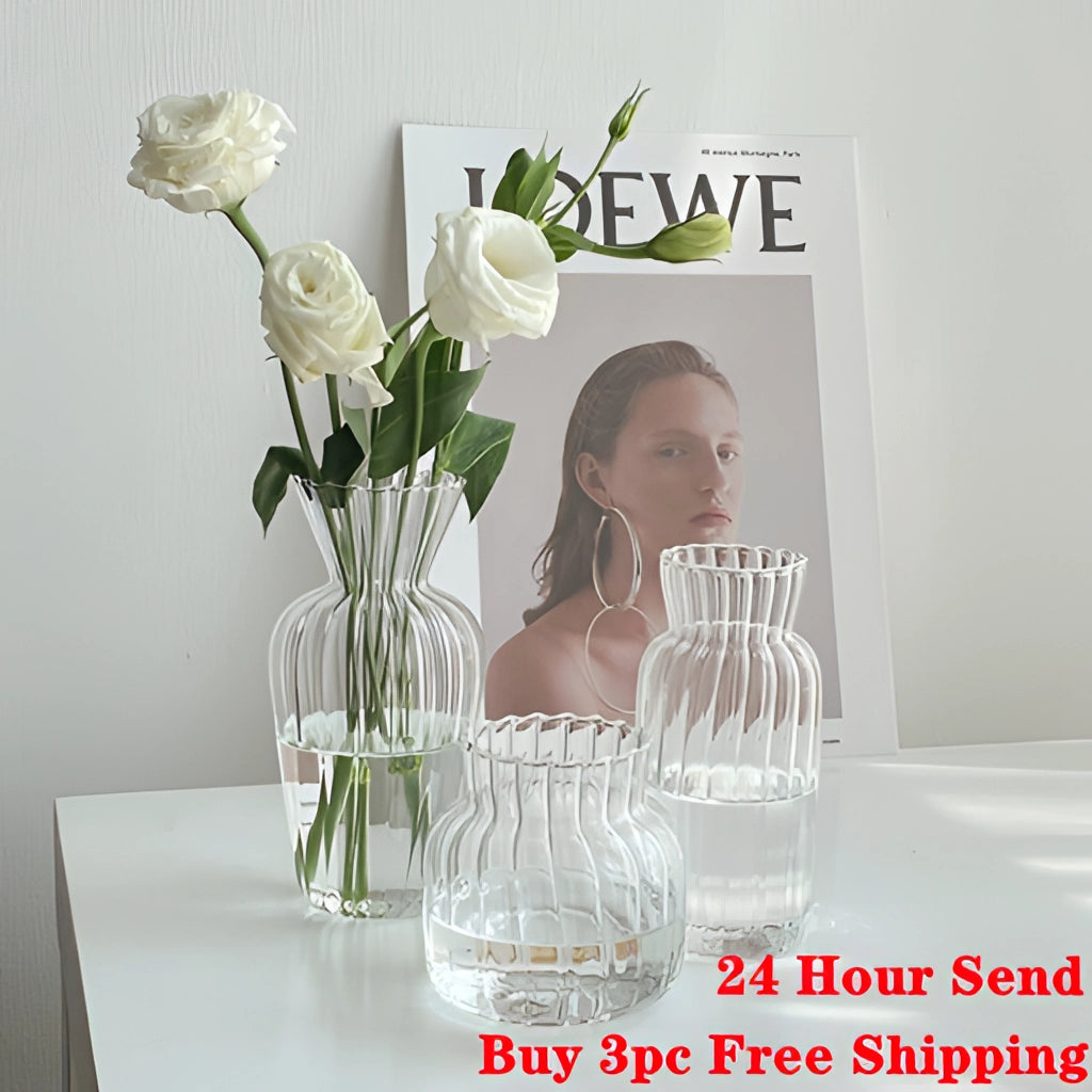Nordic style transparent glass plant vase on a table with flowers and plants arranged inside.
