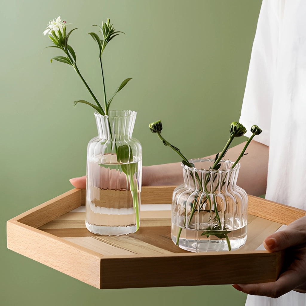 Nordic style transparent glass plant vases with flowers and branches displayed on a wooden table.