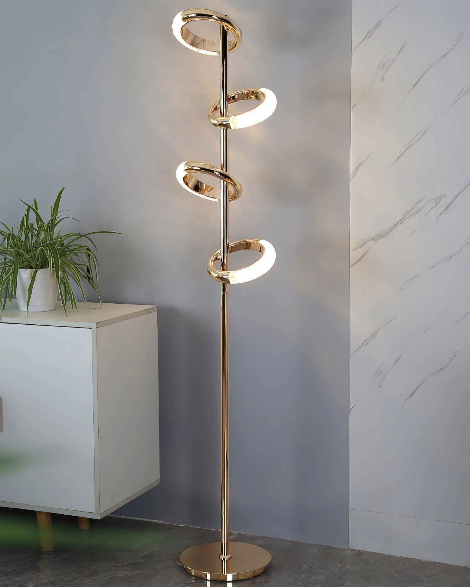A gold diamond-patterned adjustable angles floor lamp next to a wooden table and a potted plant.