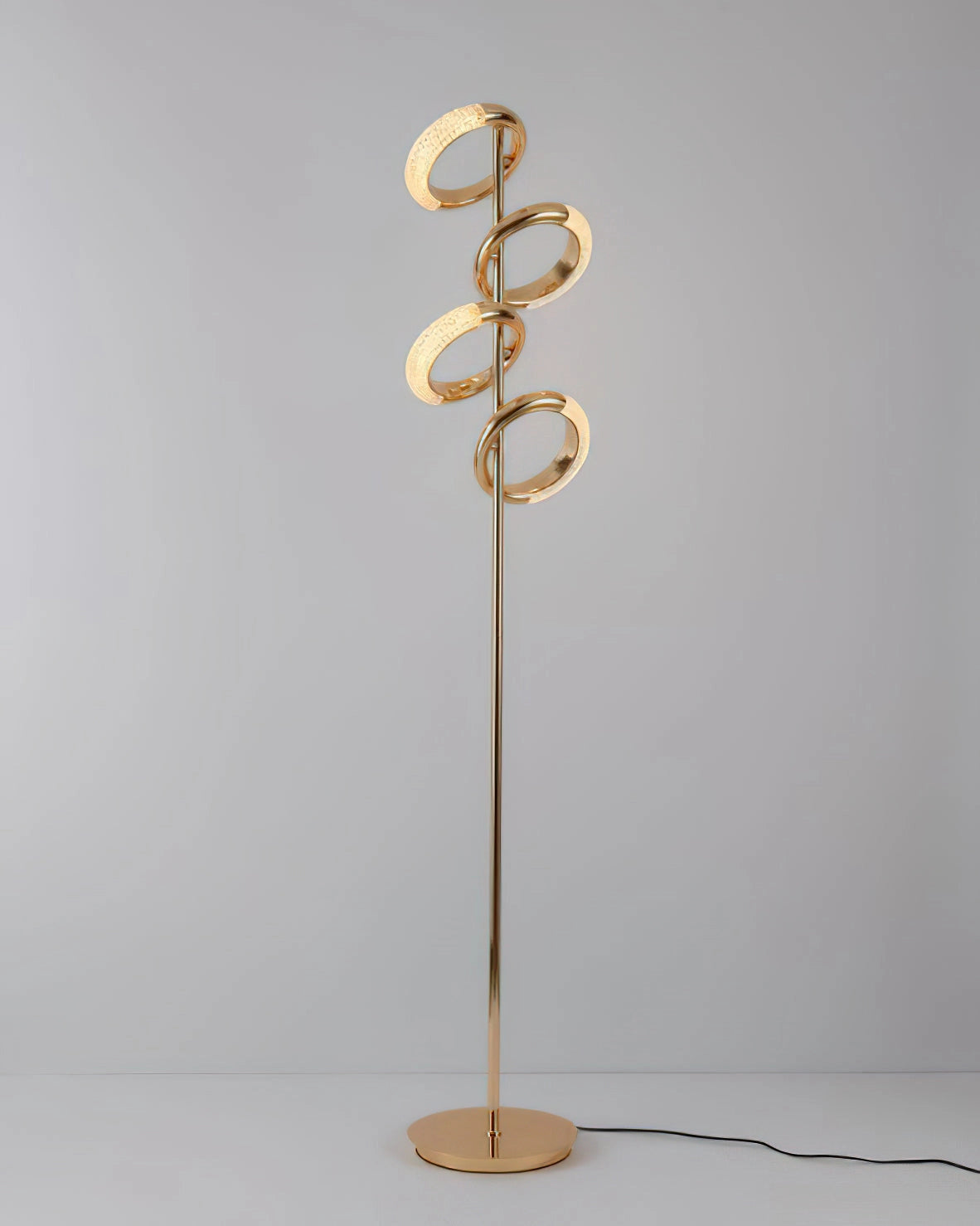 Gold diamond-patterned floor lamp with adjustable angles, standing next to a potted plant and wooden furniture.