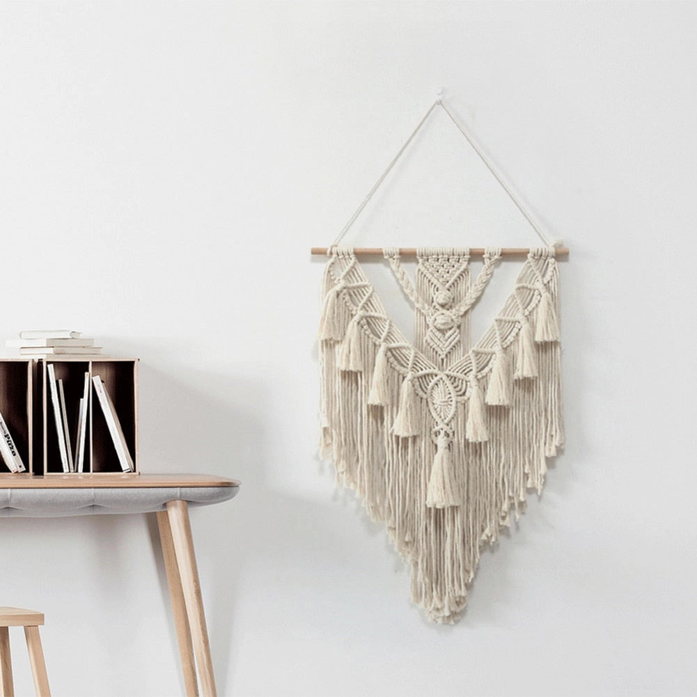 Handwoven Macrame Boho Wall Hanging Tapestry with Geometric Art Decor, featuring grey and natural wood tones, displayed on a wall above a shelf with metal and twig sculptures.