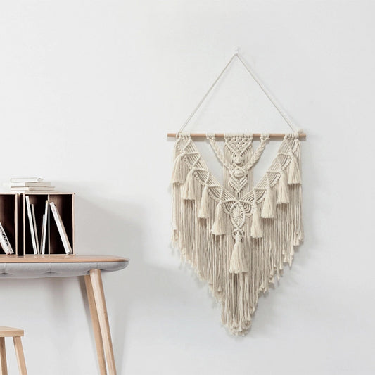 Handwoven Macrame Boho Wall Hanging Tapestry with Geometric Art Decor, featuring grey and natural wood tones, displayed on a wall above a shelf with metal and twig sculptures.