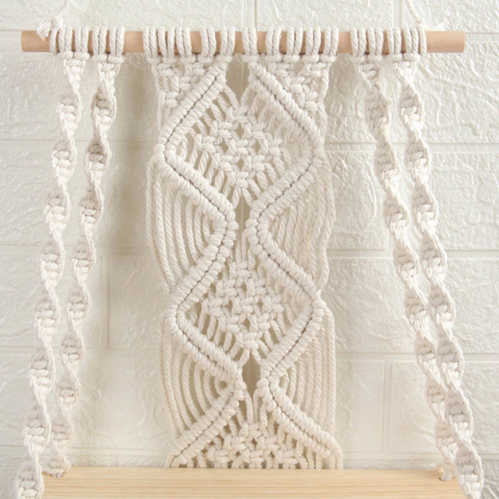 Handwoven macrame boho wall hanging tapestry with geometric art decor in brown and beige, featuring intricate patterns, displayed against a wooden background.