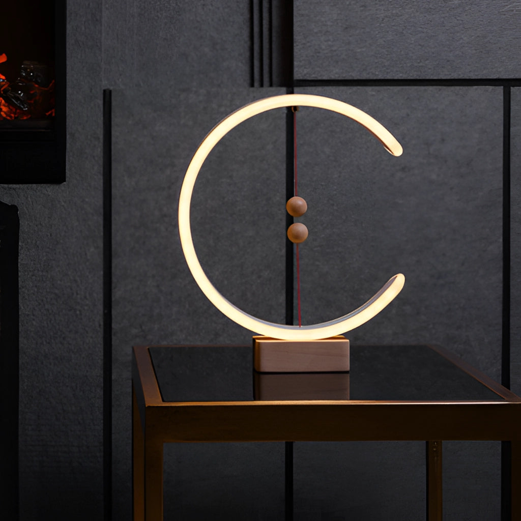 A crescent-shaped interior lamp with magnetic switches, mounted on a wooden wall with rectangular art frames and hardwood shelves.