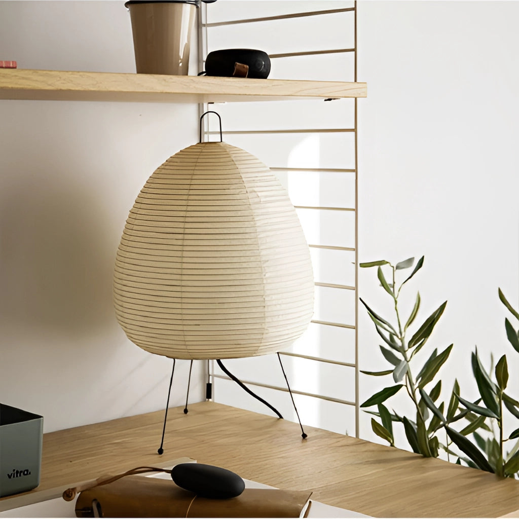 Japanese Rice Paper Table Lamp with wooden base on a table, illuminating a modern interior space with grey walls and shelving in the background.