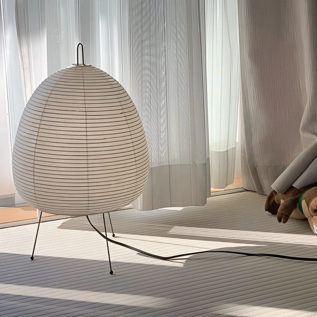 Japanese Rice Paper Table Lamp featuring a wooden base and textile shade, placed on a wooden floor in a cozy interior setting.