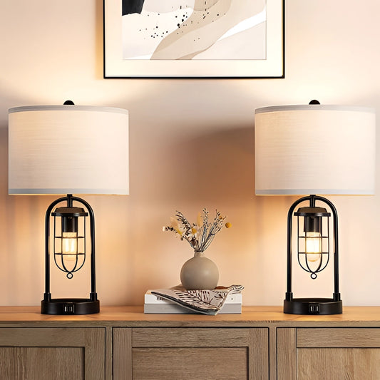 LED desk lamp with dual bulb modeling and USB ports on a white countertop, with wooden cabinetry and a green plant in the background.