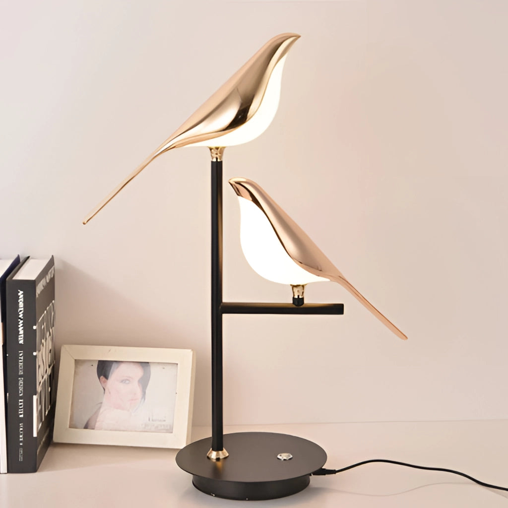 LED desk lamp with postmodern galvanized golden bird design, featuring a wooden base, metal stem, and lampshade, placed on a shelf.