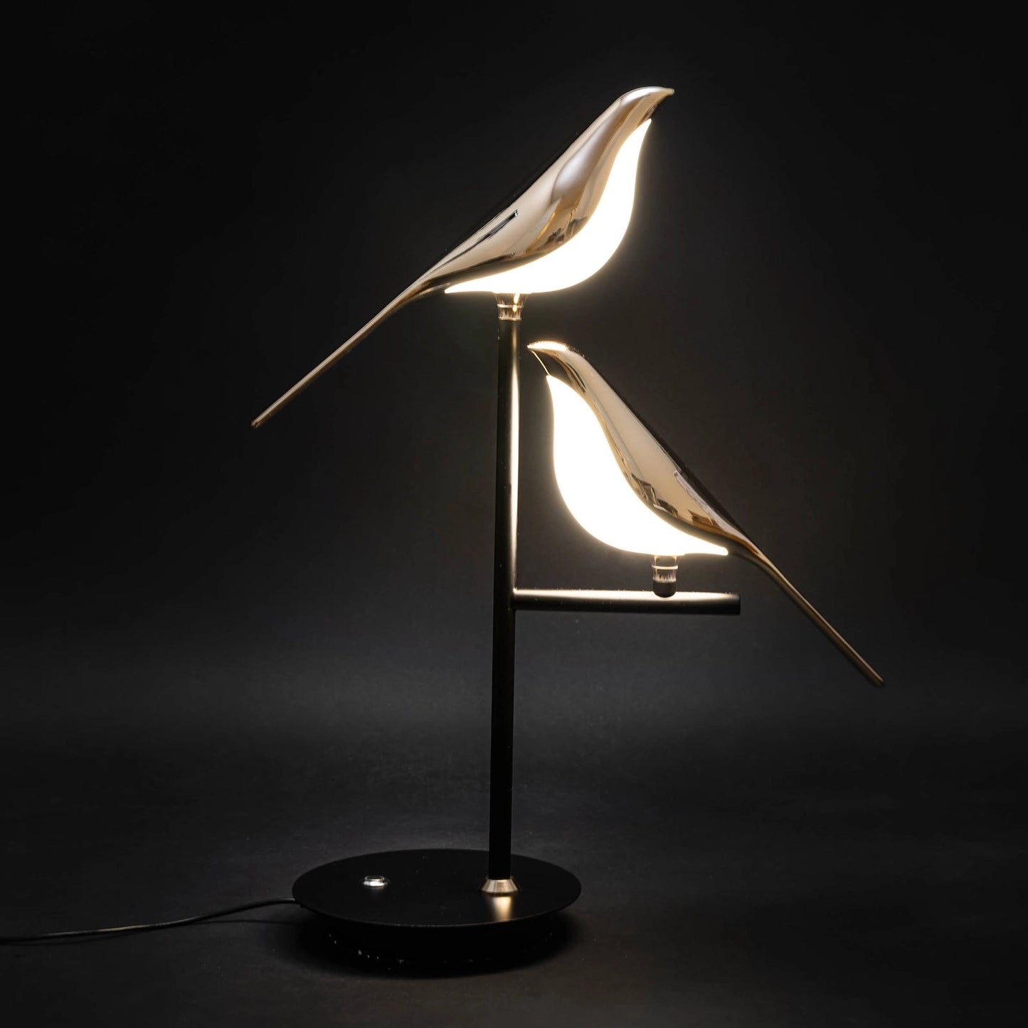 LED desk lamp with postmodern galvanized golden bird design featuring a metal bird sculpture, wooden base, and light fixture illuminating in darkness.