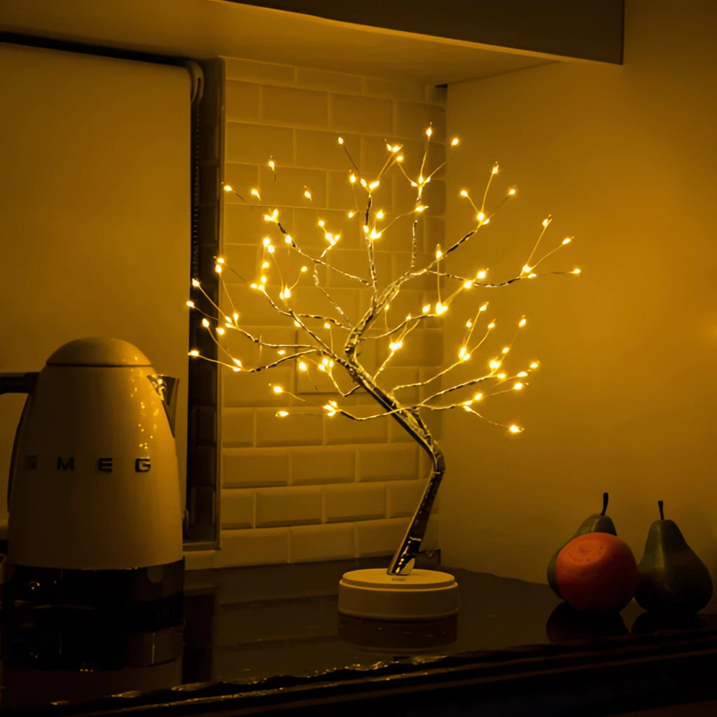 LED Fairy Tree Light with 108 Mini LEDs illuminating in a warm amber glow, resembling a small tree with twigs, placed indoors near a window, enhancing interior design with its artistic and natural wood-like appearance.