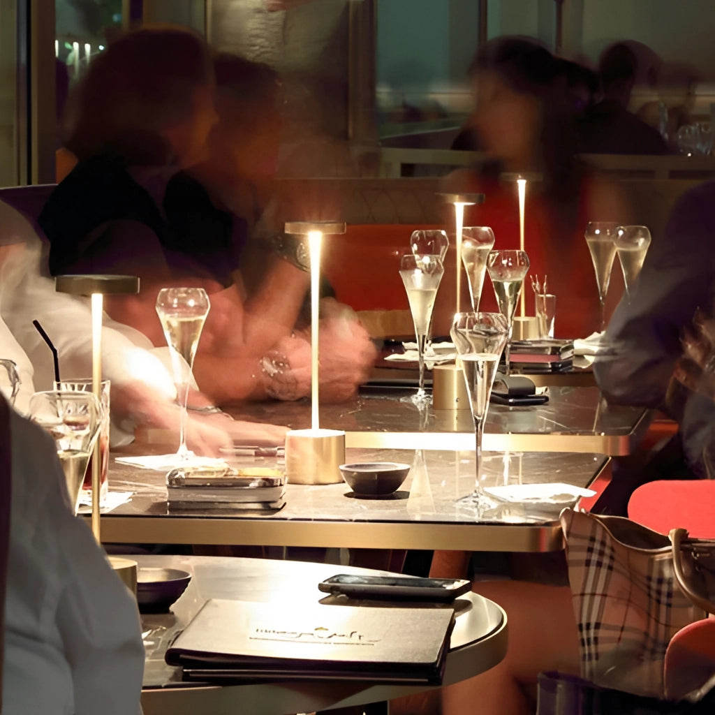 LED Portable Table Lamp with Resilient Design on a table alongside various barware and glassware items.