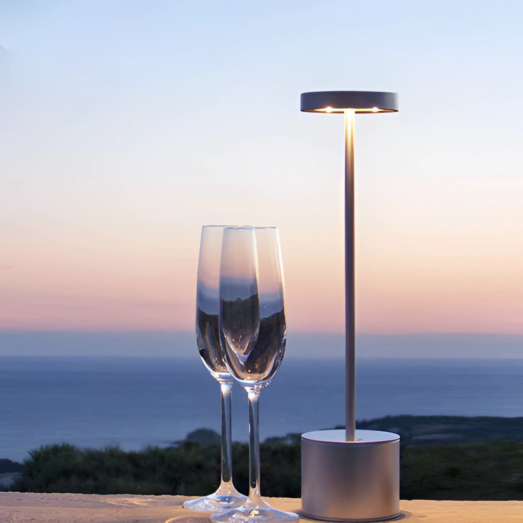 LED Portable Table Lamp with Resilient Design on a table next to a wine glass filled with liquid.