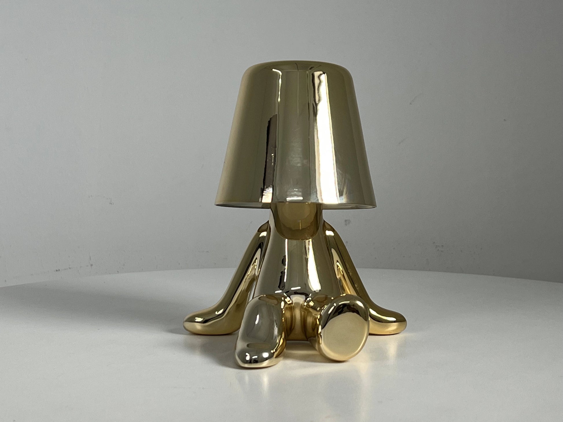 LED table lamp with unique design featuring a wooden base, metal accents, and a bronze lampshade, placed on a table next to a chair.