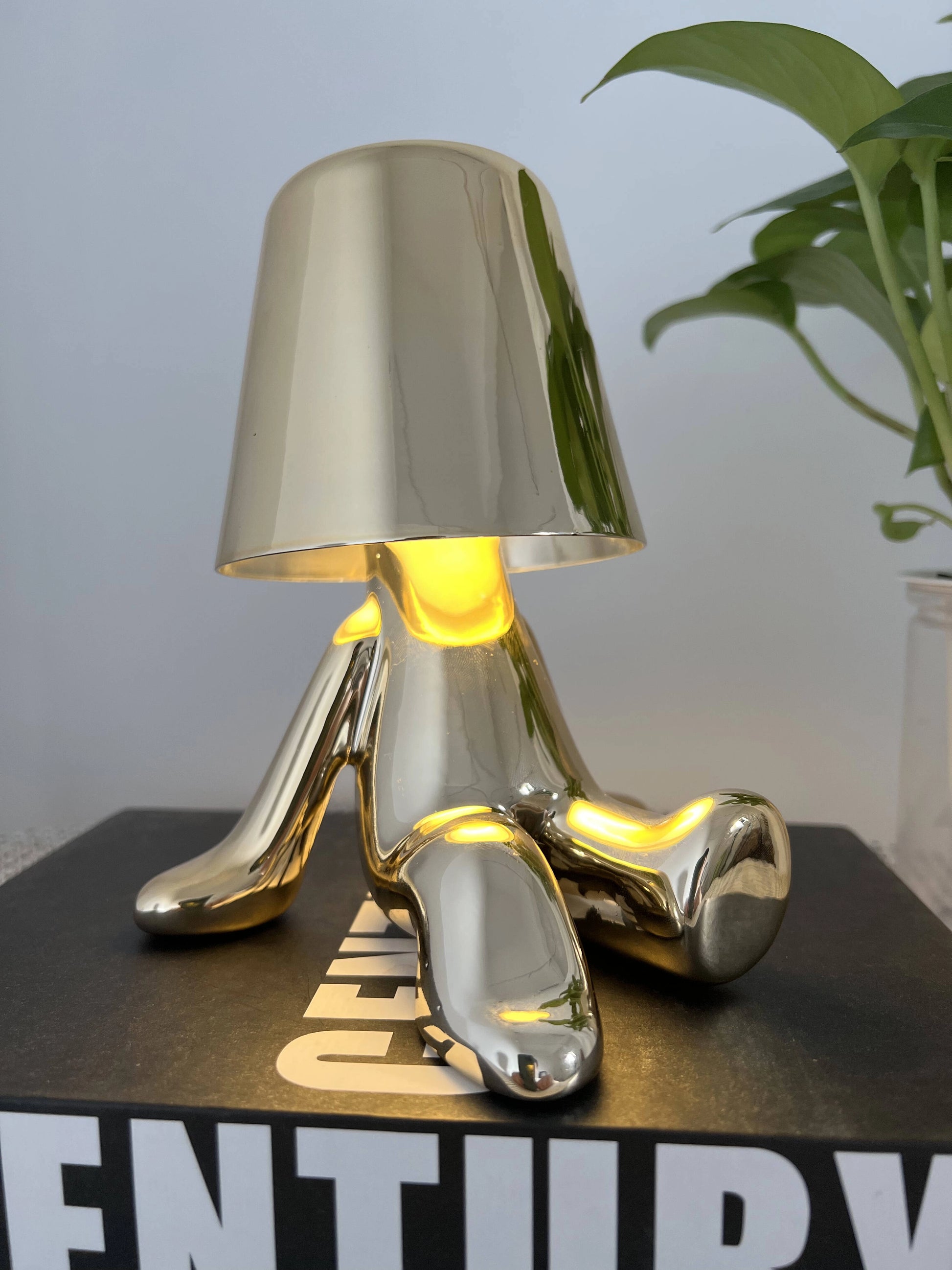 LED table lamp with unique design, featuring a sleek metal and wood base, and a modern lampshade, placed next to a small plant.