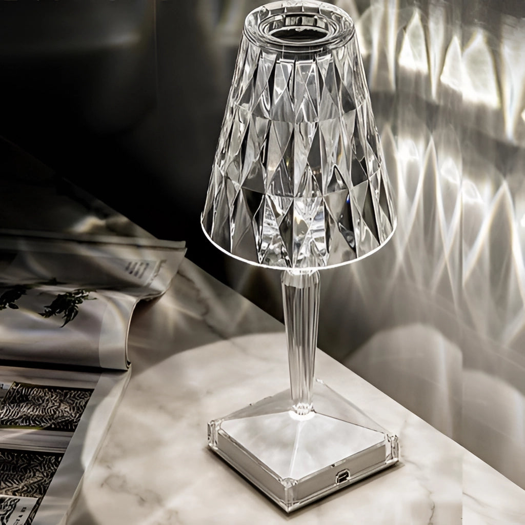 A modern LED touch table lamp with a unique design, featuring a white and black color scheme, placed on a table next to glass drinkware and barware items.