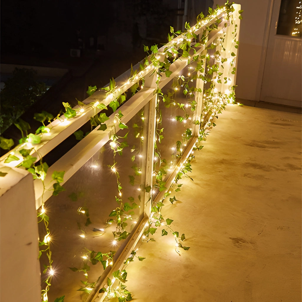 LED Vine Garden String Lights with Ivy Vines - 32ft 100 LEDs hung on a wooden structure near a door, illuminating with warm light.