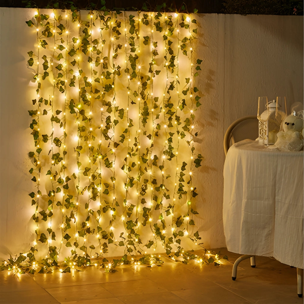LED vine garden string lights with ivy vines, 32ft with 100 LEDs, used as decoration in an interior setting featuring flooring, chairs, and ornamental plants.