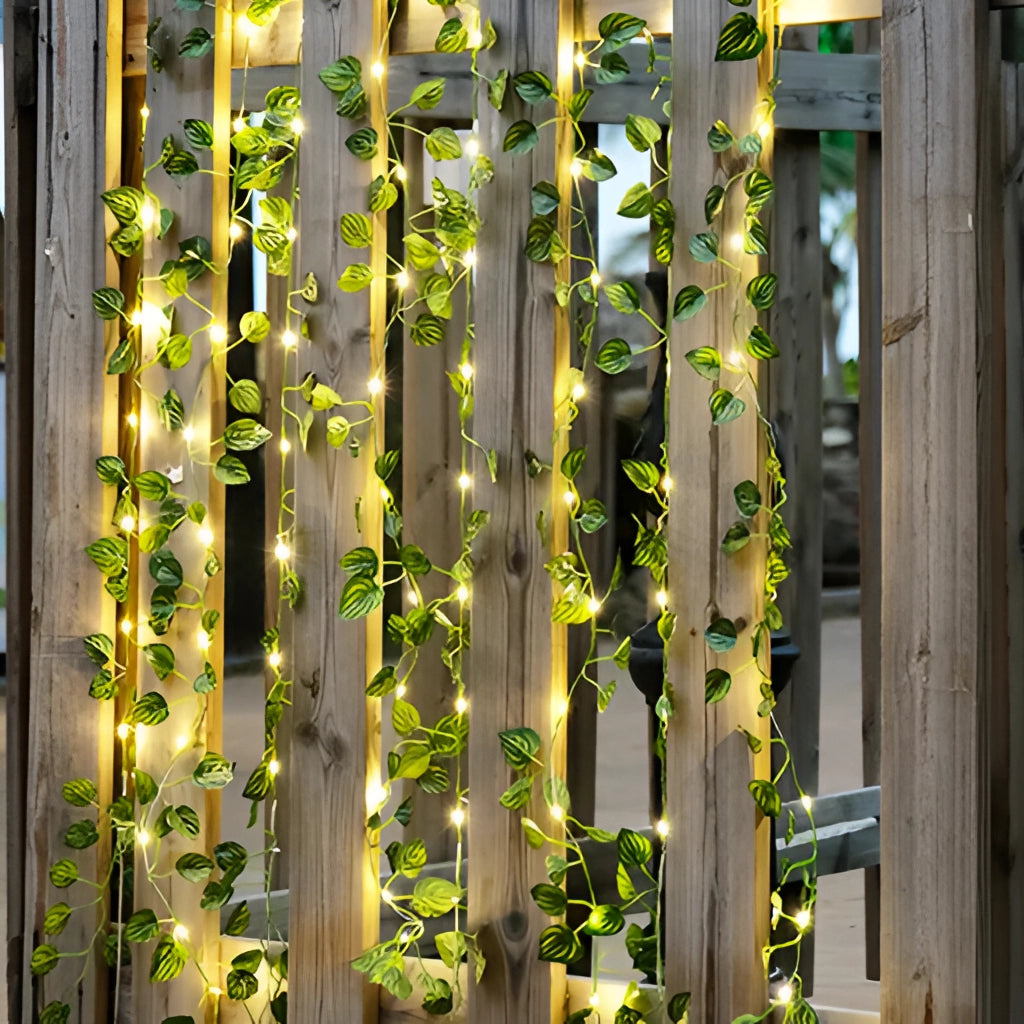 LED Vine Garden String Lights with Ivy Vines - 32ft 100 LEDs draped over wooden surface, showcasing lush green leaves and bright LED lights.