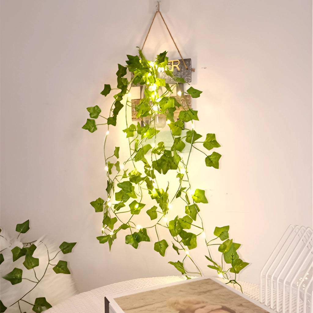LED Vine Garden String Lights with ivy vines wrapped around a 32ft length, featuring 100 LEDs, displayed in a room with houseplants and floral decorations.