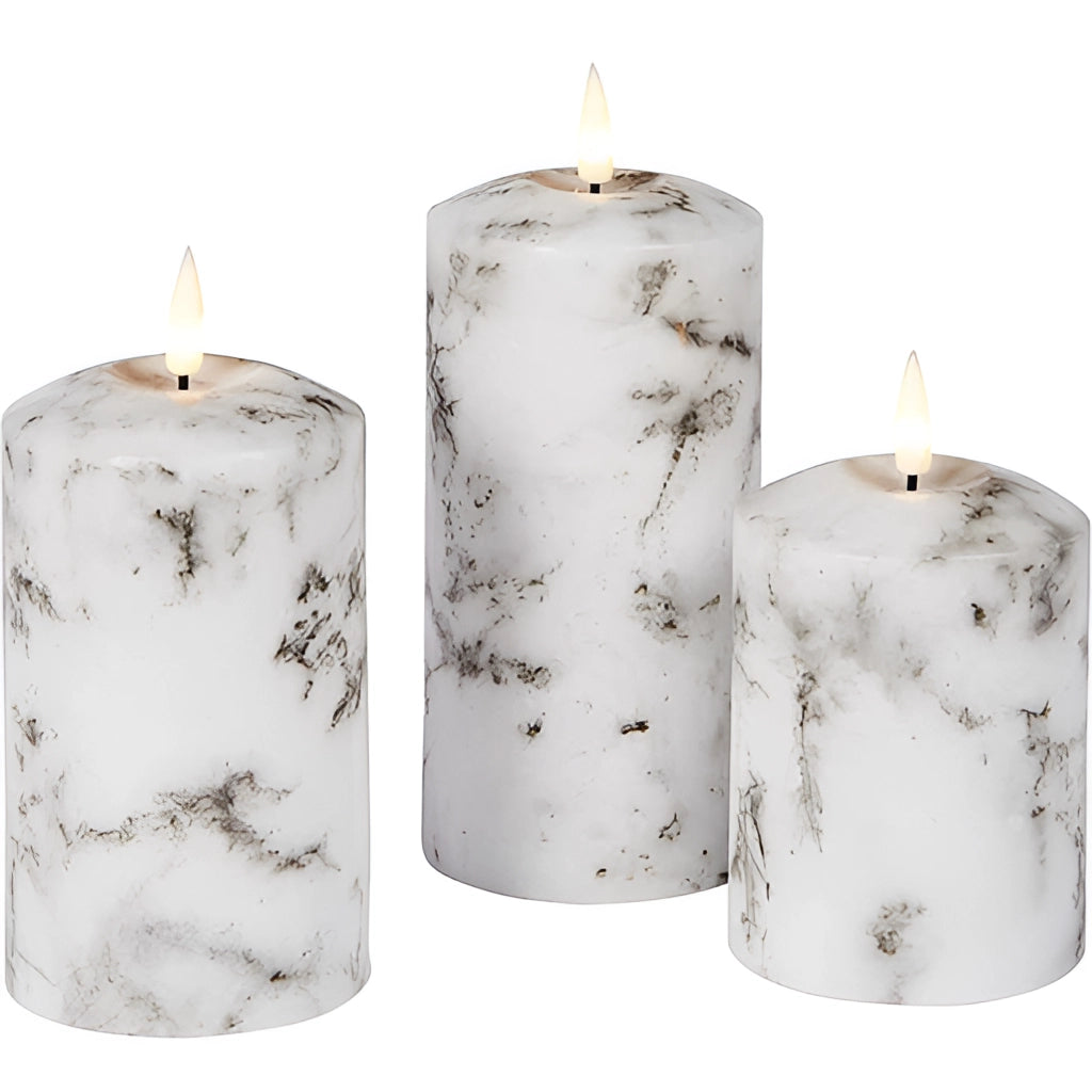 A trio of flameless LED candles with a marble design, featuring wax exteriors and cylindrical shapes, displayed in a stylish setting.
