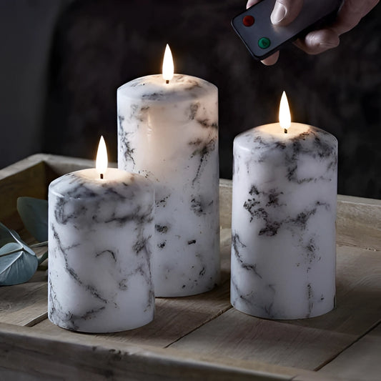 A set of three marble LED flameless candles emitting a warm glow, resembling real candles without the flame.