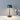 Green metal table lamp with adjustable brightness, sitting on a table next to a vase with flowers.