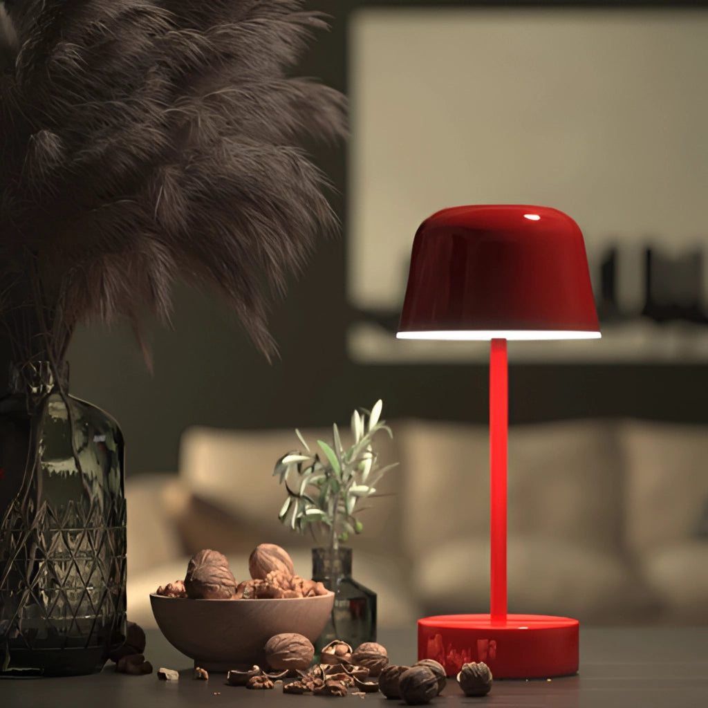 Metal Table Lamp with Adjustable Brightness - Pulse Flare, placed on a rectangular table next to a flowerpot with a houseplant, in a well-lit room with flooring.