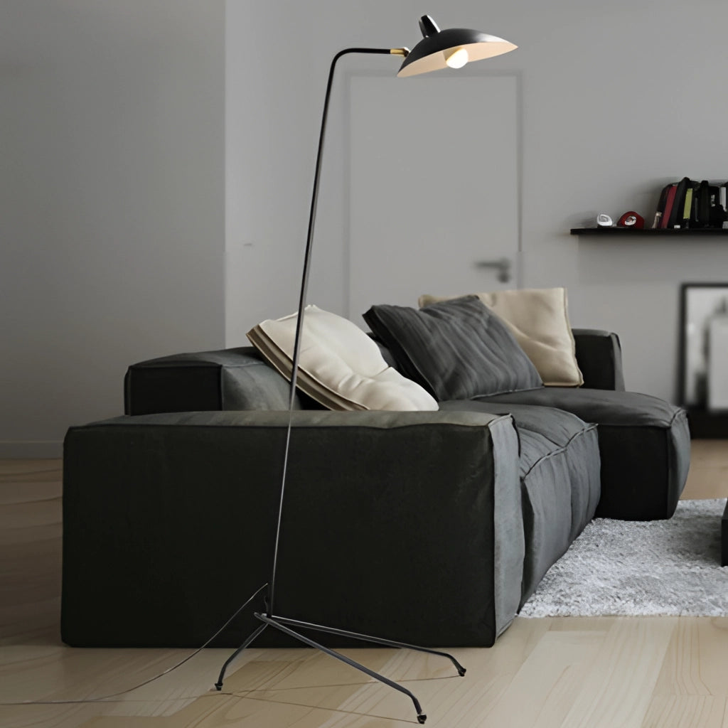 Midcentury floor lamp with tilting heads placed next to a grey couch in a modern living room with wood flooring.