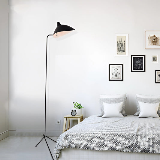 Midcentury black floor lamp with tilting heads next to a picture frame in a cozy bedroom setting with wooden flooring.