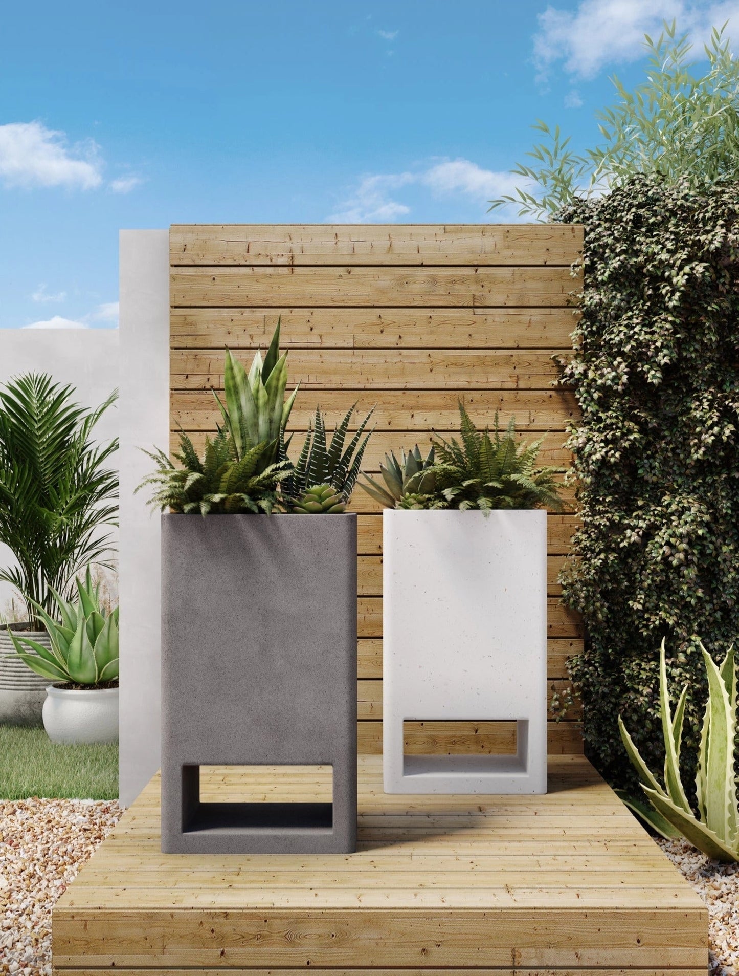 Ivory terrazzo garden planter with a green plant, placed outdoors near a wooden wall and grassy area under a partly cloudy sky.
