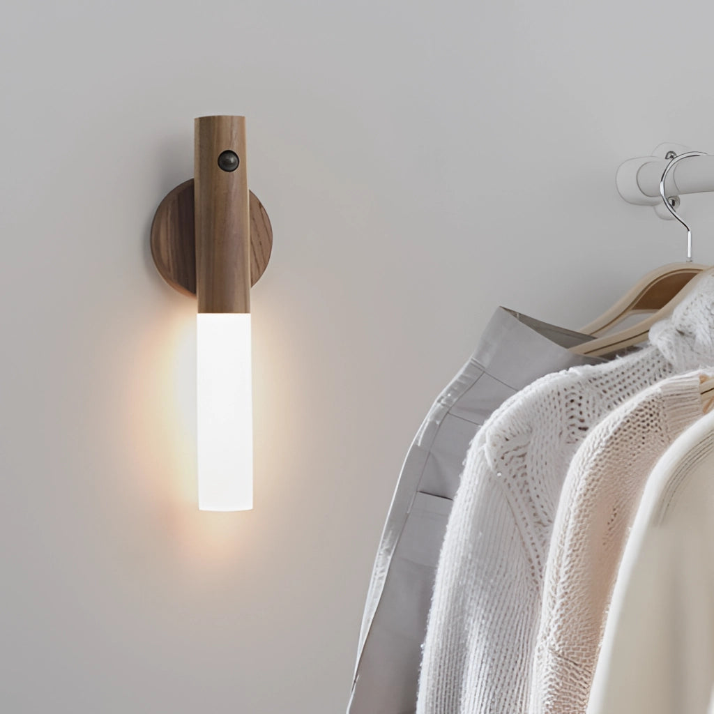 Motion Sensor LED Rechargeable Night Light with Wooden Design mounted on a wall near hanging formal clothes and a dress shirt on a hanger.