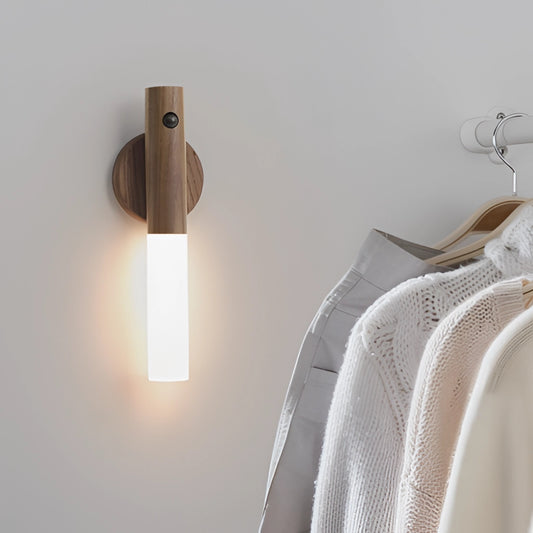 Motion Sensor LED Rechargeable Night Light with Wooden Design mounted on a wall near hanging formal clothes and a dress shirt on a hanger.