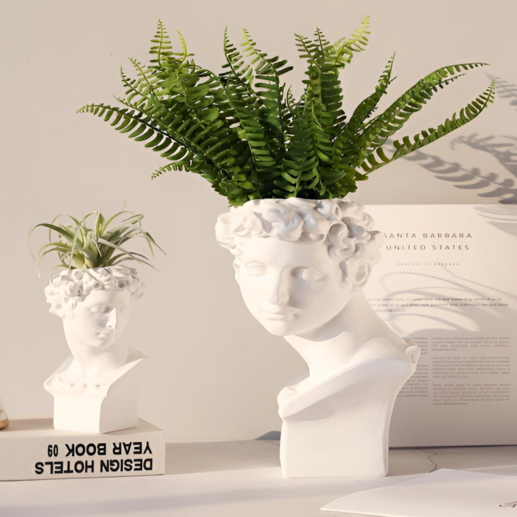 Neoclassical Greek head resin vase with houseplant on a rectangular base.