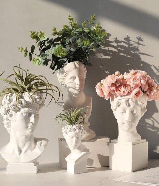 Neoclassical Greek head resin vase planter with houseplant and flowers, used as a decorative artifact in interior design.