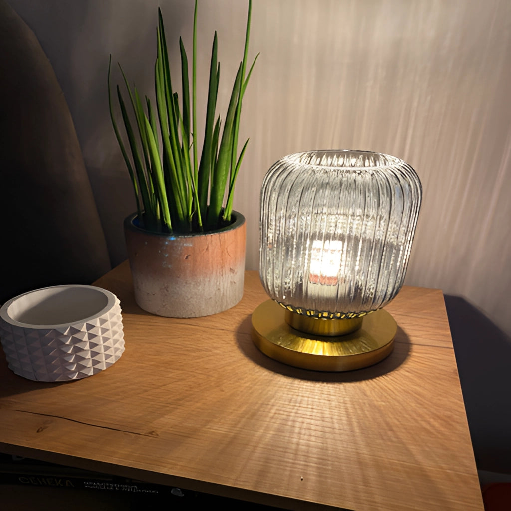 Nordic Amber Table Lamp with Stained Glass Shade placed on a wooden table next to a green houseplant in a flowerpot, showcasing a stylish interior design.