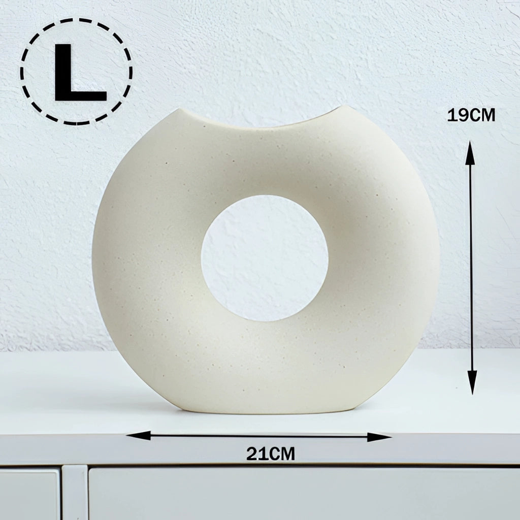 Nordic style ceramic donut vase with a modern circular design displayed on a wall shelf in a living room.